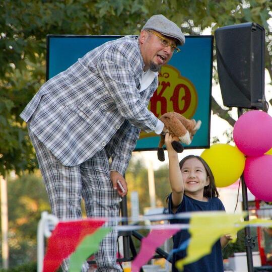A smiling girl receiving a stuffed animal from Wacko